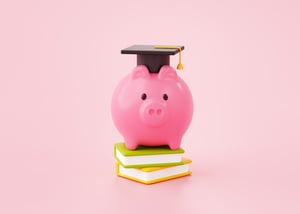 Tirelire en forme de cochon rose posée sur des livres, portant un chapeau de diplômé – symbole de l’éducation financière